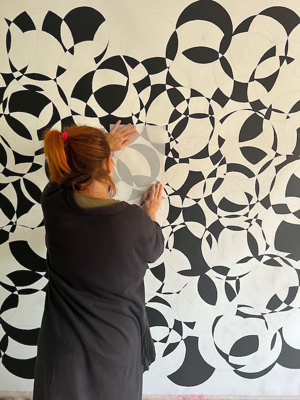 Marina Orlova creating geometric black-and-white mural on studio wall