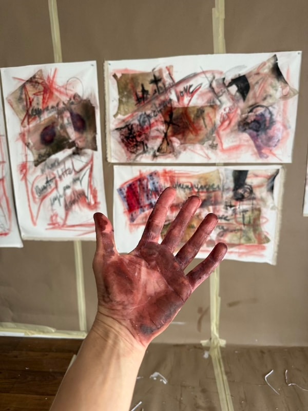 Marina Orlova with paint-covered hands displaying studio artwork