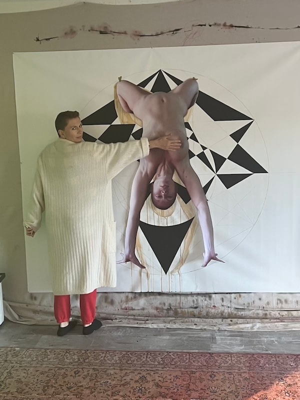 Marina Orlova posing with inverted acrobat artwork in studio