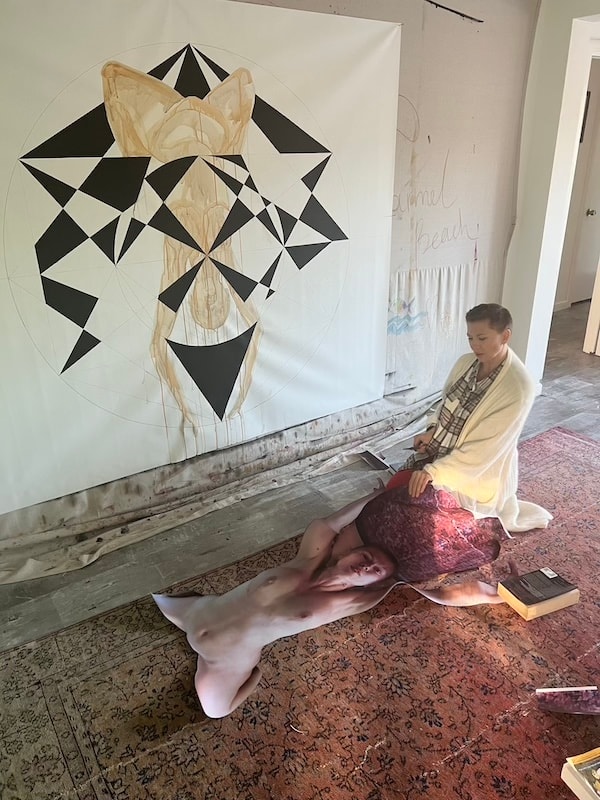 Marina Orlova seated beside geometric wall mural in studio