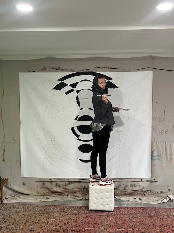 Marina Orlova on stool painting large geometric canvas in studio