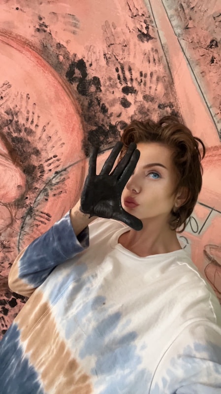Marina Orlova posing against abstract pink mural in studio